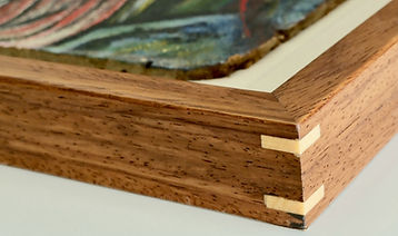 Detalle de la esquina de un marco de madera artesanal con llaves de ensamblaje en contraste y pintura flotante