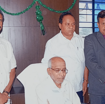 Group of five men, one seated wearing glasses