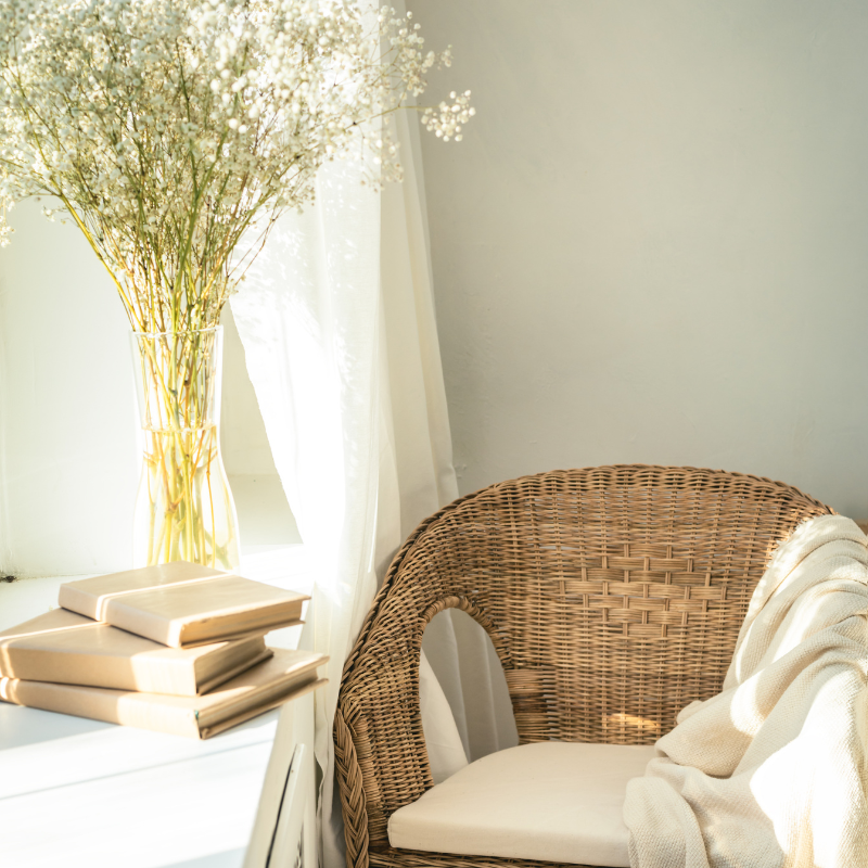 A reading nook with a wicker chair and books by a window,