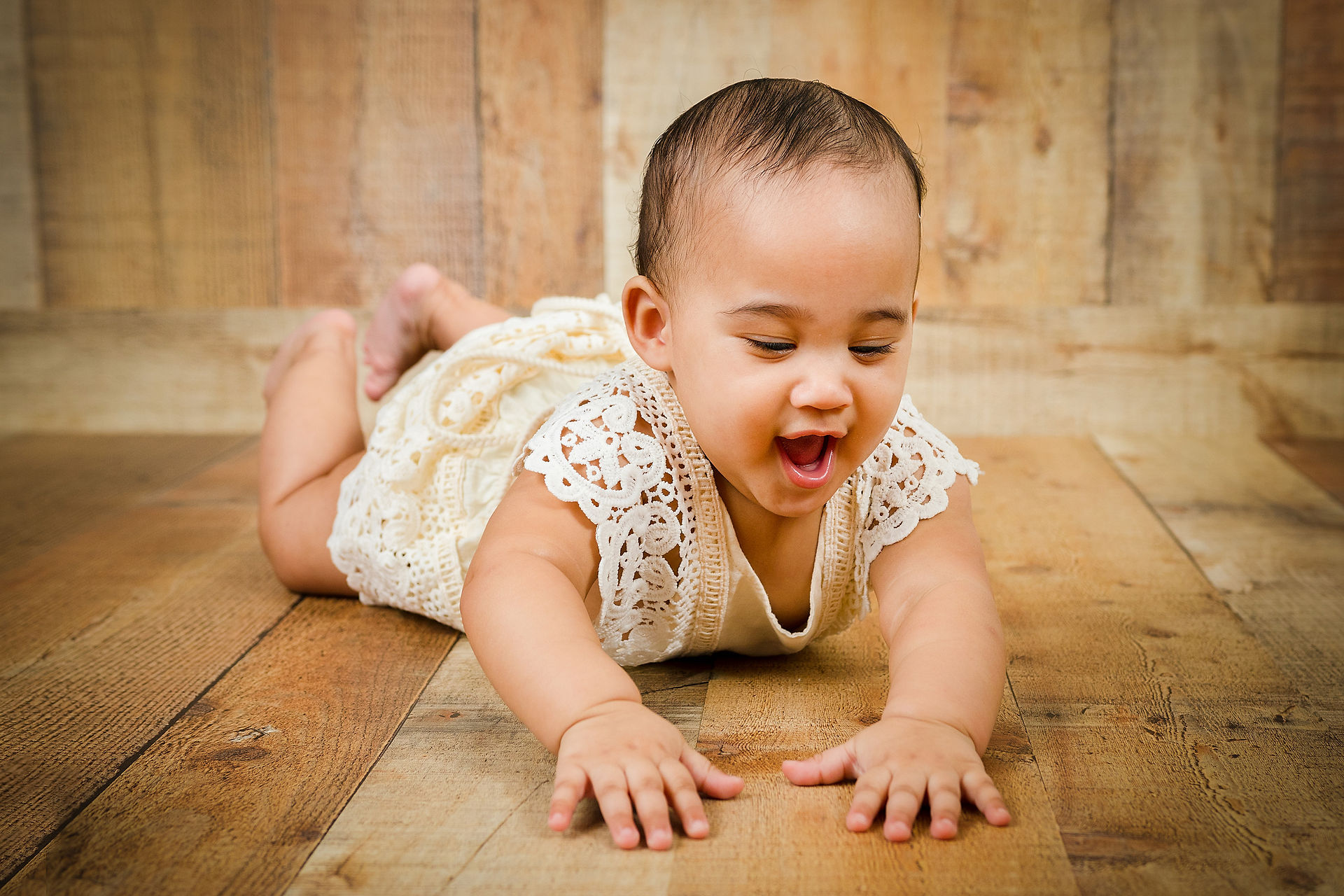little girl laying on her tummy, toddler, toddler photograph, sitter session, wooden background, baby photo, children photographer, portrait, miami photographer, baby photographer, miami,