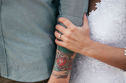 Walt & Roy close-up photograph of a wedding photograph of a wife's wedding ring holding her husband's arm.