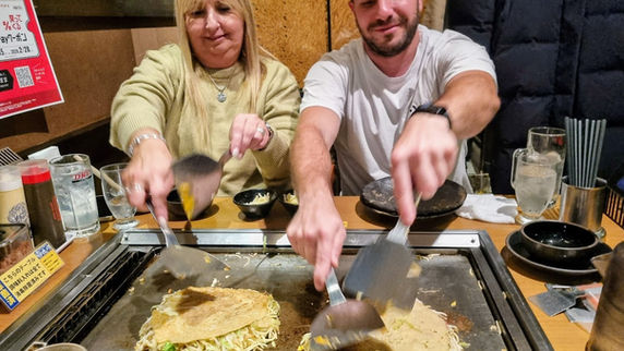 Two customers making their own okonomiyaki