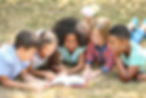 Cute kids reading book on green grass.jp
