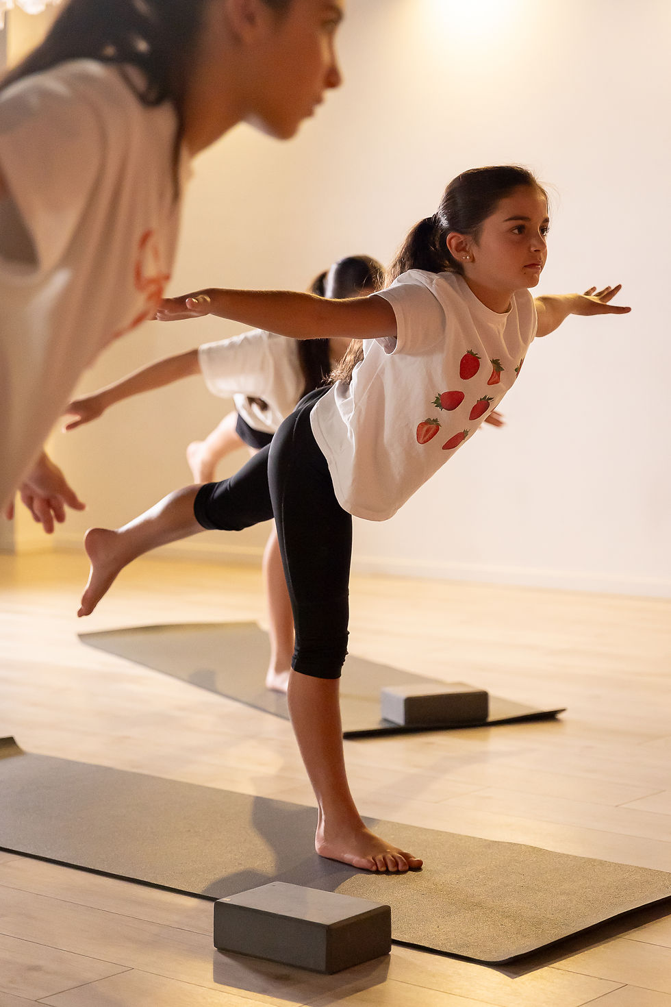 Eye-level view of a child practicing yoga on a mat in a bright classroom