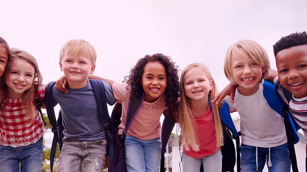 Group of diverse smiling elementary school children standing together outside.