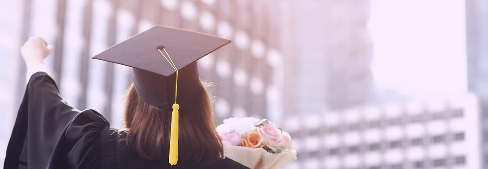 A high school graduate in a cap and gown raising their fist in celebration while holding a bouquet of flowers, standing against a bright city skyline.