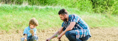 A father and son are planting trees in a field, illustrating a shared commitment to nature and family values.