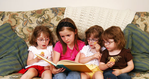 Three girls on a couch, sharing a book and enjoying their reading time.