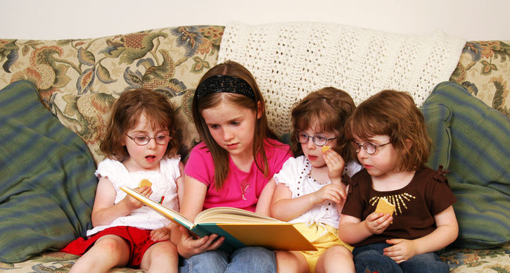 Three girls on a couch, sharing a book and enjoying their reading time.
