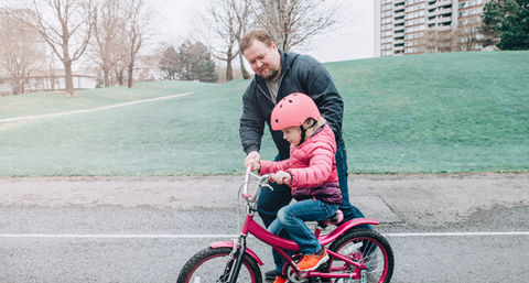 Father and Daughters happily cycling together, sharing a moment of joy.