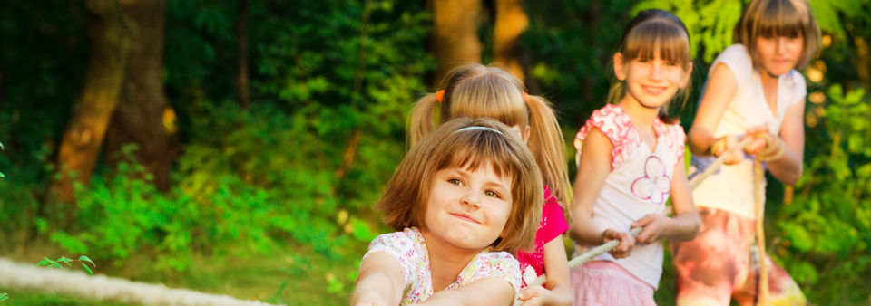 Children joyfully playing with a rope on green grass, engaging in a fun outdoor activity together.
