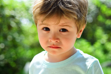 A young boy looks at the camera with a sorrowful face, reflecting his feelings of sadness.