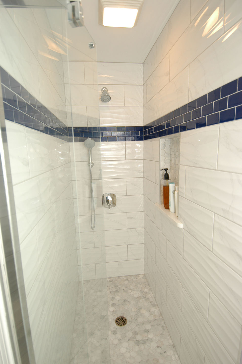 Walk-in shower with porcelain tile, marble floor, and Grohe multi-function handheld shower system