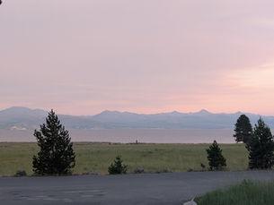 Hazy red skyline from setting sun over lake with fog