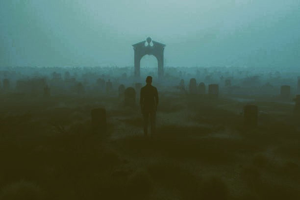 Silhouette of a person standing in a foggy, eerie cemetery with headstones and a distant arched gate. Moody, mysterious atmosphere.