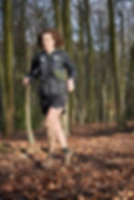 Femme habillée en noir, courant dans les bois et la boue sous le soleil