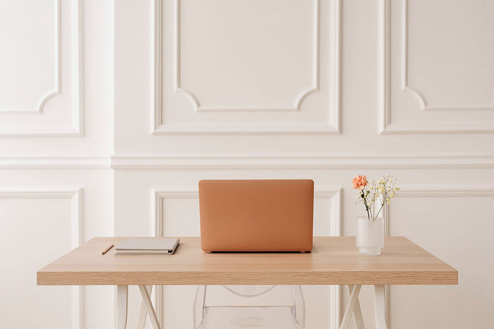 A laptop displaying financial data on a wooden table with a small flowering plant.