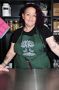 Older woman standing behind steel table. She is the owner/founder of the company.