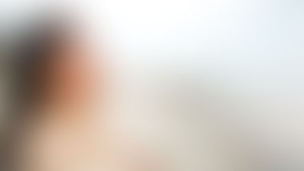 A woman at the beach with her eyes closed and and a smile on her face