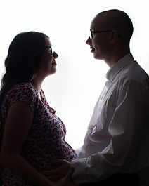Couple sharing a moment of love during maternity photoshoot with high key backlit style