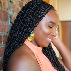 Side profile of young black woman smiling against brick wall.