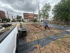 Two workers preparing dirt in an urban landscaping site