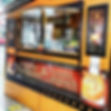 Der Foodtruck Bretz Baumstrietzel ist ein Holzstand mit Ausgabefenster; Schilder für Baumstriezel und herzhafte Langosch.