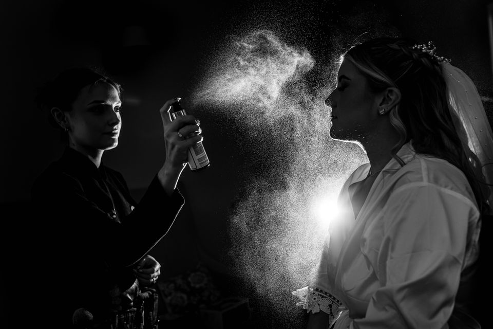 Spray from the fixing spray frozen in time as its is sprayed onto the brides face in the bridal suite at doddington hall wedding venue in Lincoln