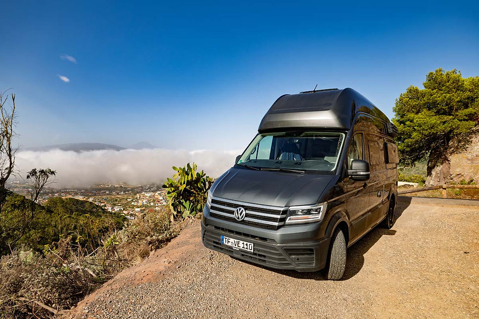 VW Grand California 600 from vanXcapes parked at a Tenerife viewpoint above a sea of clouds with a village below