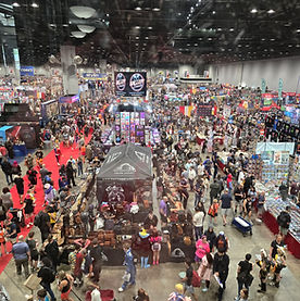 Crowded convention floor at MEGACON Orlando with thousands of attendees, vendor booths, and red carpet aisles; inset selfie in the foreground shows a man looking out over the event.