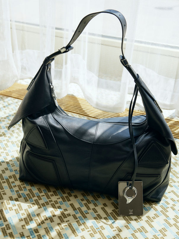 For his Spring/Summer 2025 menswear collection, David Koma unveiled a refreshing take on masculinity—cool, sensual, and brimming with controlled flamboyance. Set against sleek marble backdrops in Paris, the presentation was a balancing act between precision and play, elegance and ease.
Koma’s signature sculptural aesthetic softened here, reimagined through sheer mesh layers, gauzy knits, and relaxed tailoring. Floral appliqués bloomed on lapels, tank tops, and cardigans, suggesting a romantic counterpoint to the sharply tailored trousers and oversized outerwear. The footwear? Flip-flops. A casual wink to the collection’s breezy undercurrent, nodding to spontaneity and grounded luxury.
Textures were key: buttery leather met delicate embroidery, and glimmering beading contrasted with laid-back jersey. Accessories, such as oversized totes and standout millinery, punctuated the looks with quiet drama. Beauty was raw, clean-skinned, and lived-in—emphasizing a nonchalant, real-world charm.
The palette remained faithful to neutrals—black, white, olive, and muted tones—yet the pieces pulsed with life through thoughtful layering and playful contrast. It was less about overt statements and more about a confident, modern rhythm—one that allows softness to coexist with strength.
Koma's first men’s offering feels like a deliberate, luxurious fall into ease. It doesn’t scream for attention; it holds it.