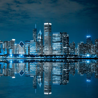 Chicago commercial skyline at night reflecting across the water.