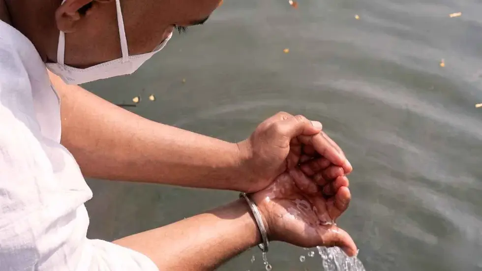 Man offering water during Pitru Tarpan ritual in river for ancestors in Hindu tradition