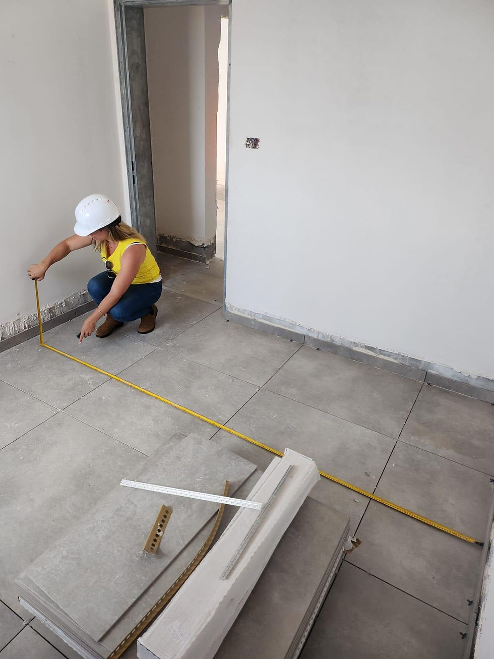 Ari Isaac measuring floor tiles during an apartment renovation.
