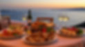 table full of greek food on a table overlooking the sea at sunset.jpg