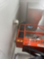 Worker on orange scissor lift in a service gallery