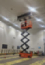 Worker on a scissor lift in an industrial gallery.