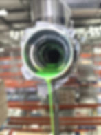 Green liquid pouring from industrial pipe in a gallery.