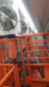 Industrial fans in a gallery of orange metal scaffolding.