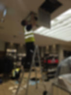 Technician on a ladder repairing a ceiling vent gallery