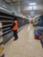 Worker in high-vis vest cleaning empty gallery shelves.