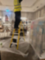 Worker on a ladder in a retail store gallery