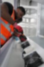 Technician in safety vest repairing fans in a gallery.