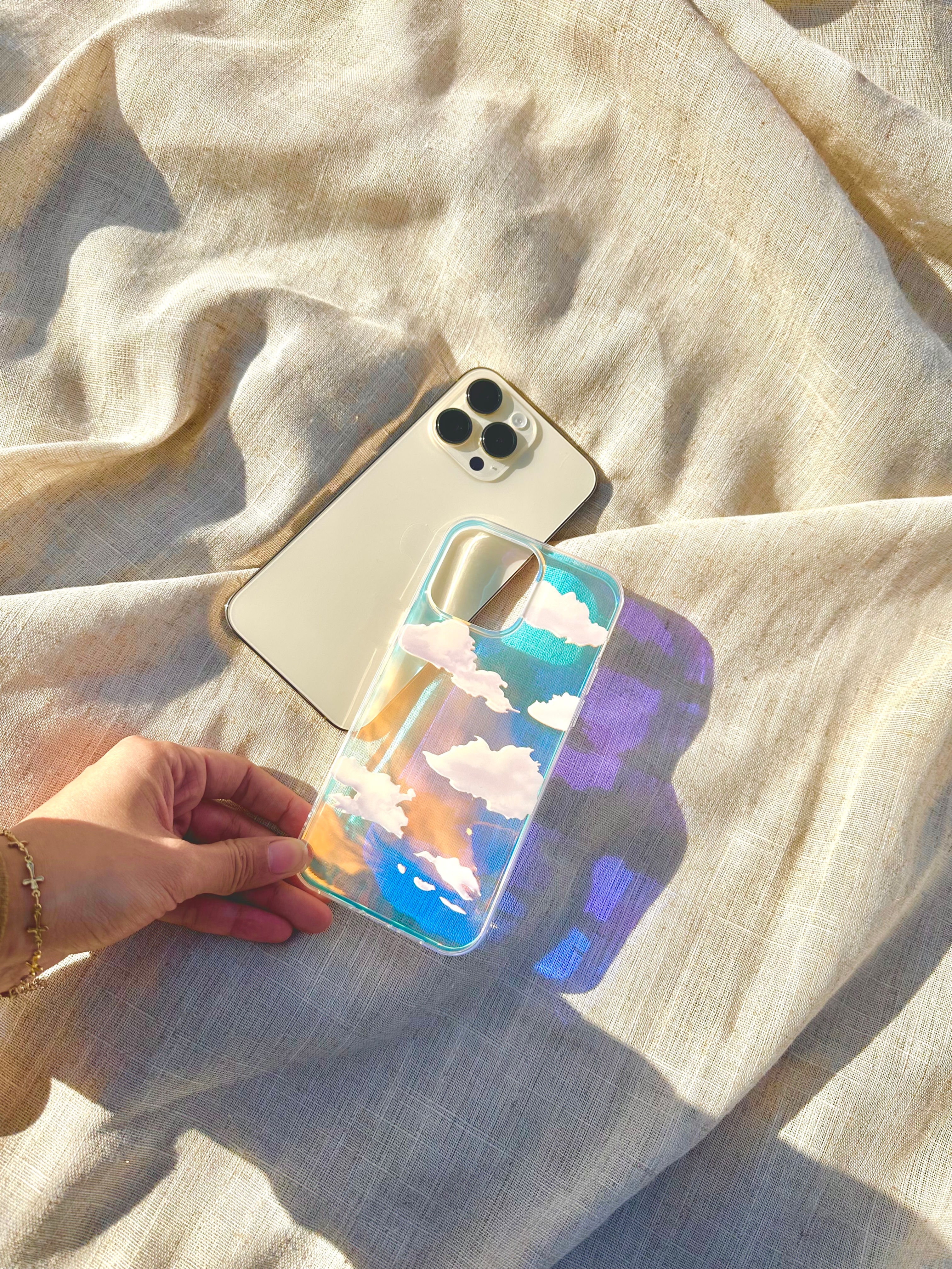 Shimmering holographic phone case with adorable cloud patterns, perfect for adding a touch of magic to your iPhone.