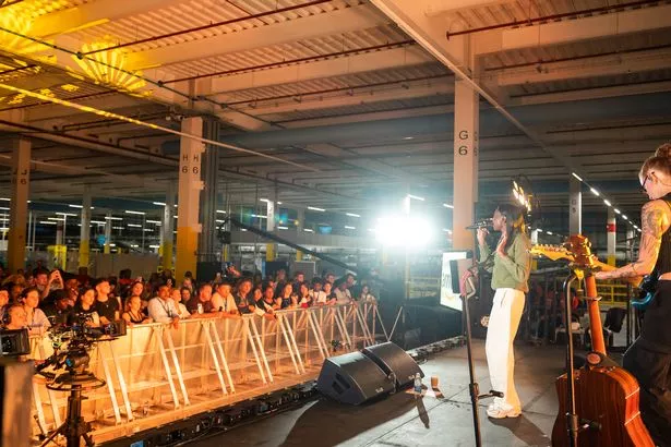 Singer Cat Burns performing inside an Amazon fulfilment centre with Apprentice Nation