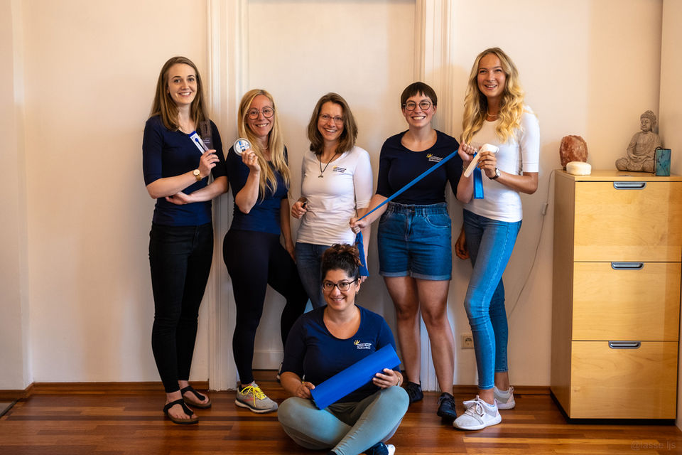 Ergotherapie-Team im Behandlungsraum mit Therapiegeräten in den Händen