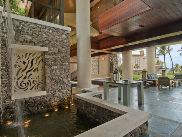 Covered Walkway with Water Feature – A resort walkway with natural stone walls, cascading water features, and an open-air seating area designed for relaxation.
