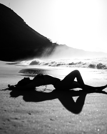 Frau liegt sinnlich am Strand.