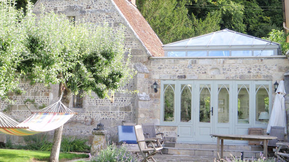 Small orangery with solid roof, tall sash-style windows, and brickwork exterior