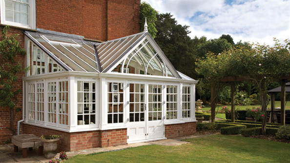 Large Victorian-style hardwood conservatory attached to a period red brick home